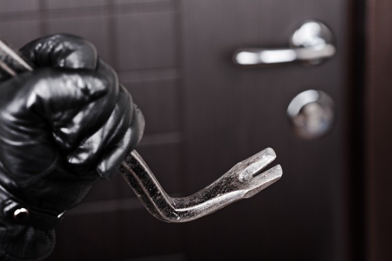 2445865-burglar-hand-holding-crowbar-break-opening-door